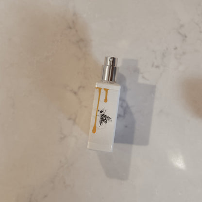 Small white bottle with a bee design on a marble surface