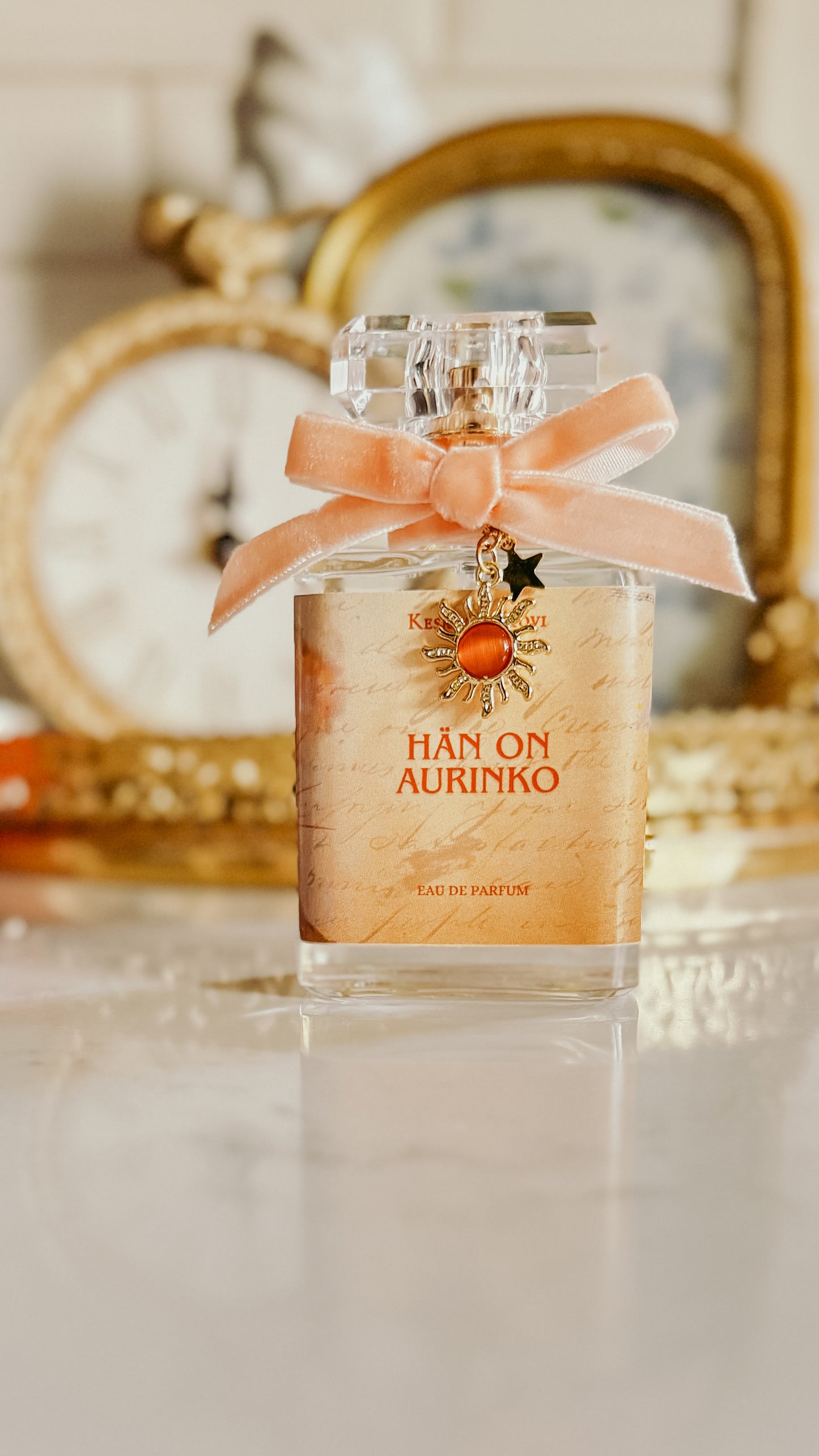 Perfume bottle with a pink bow and decorative elements on a reflective surface.