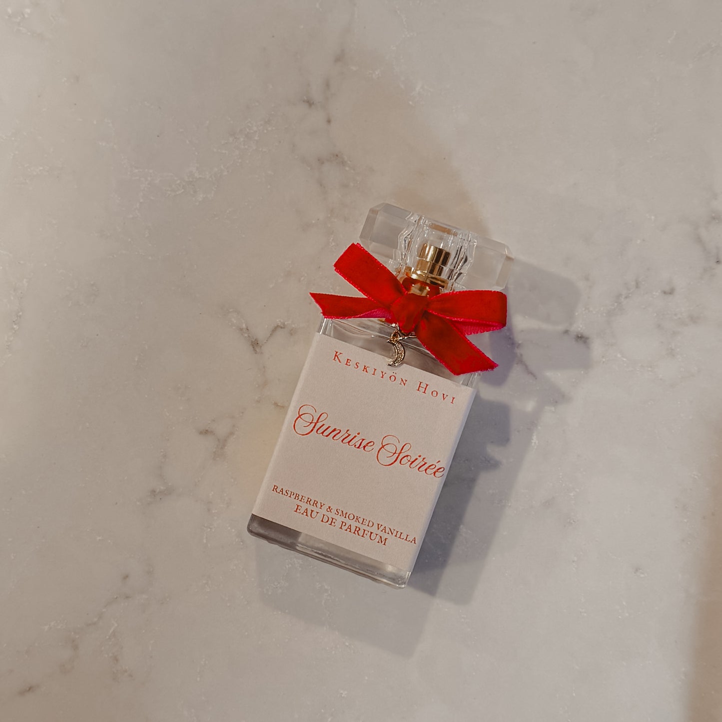 Perfume bottle with a red bow on a marble surface