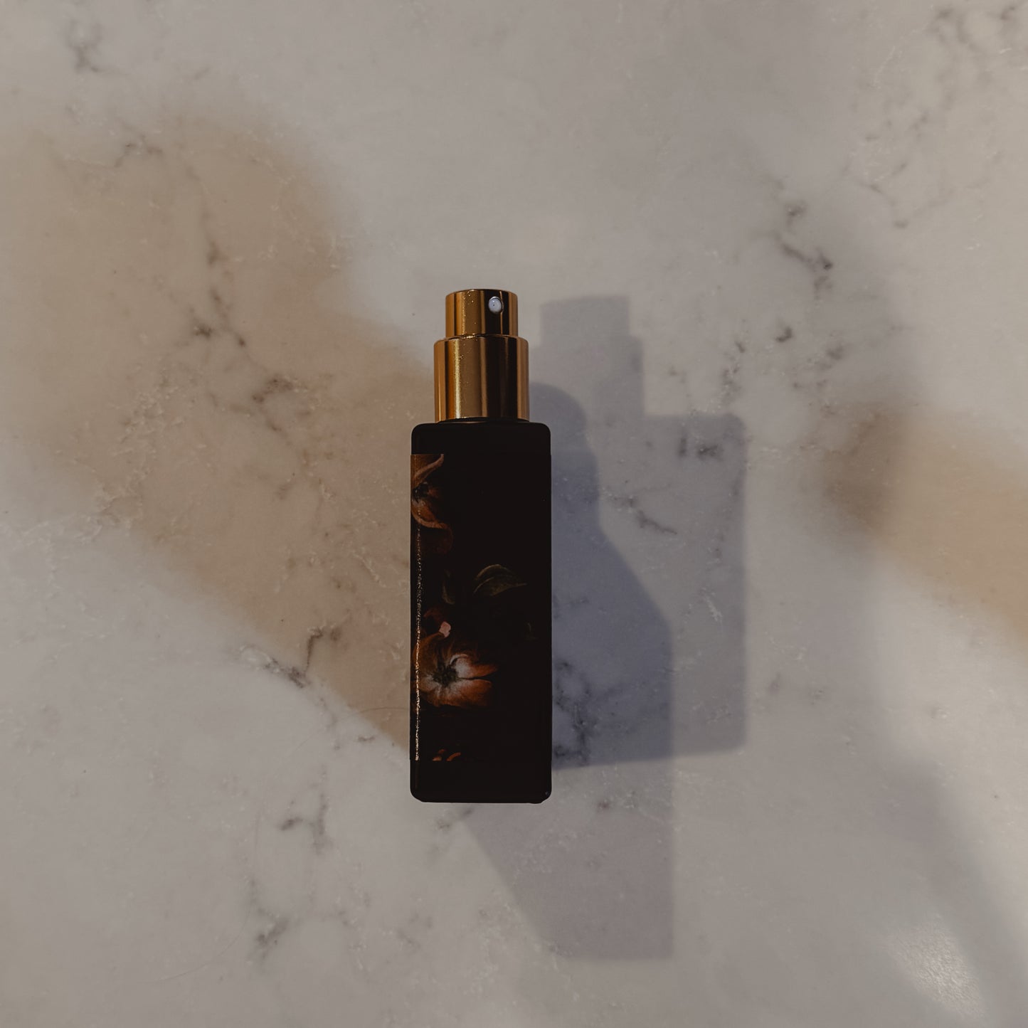 Black and gold spray bottle on a marble surface