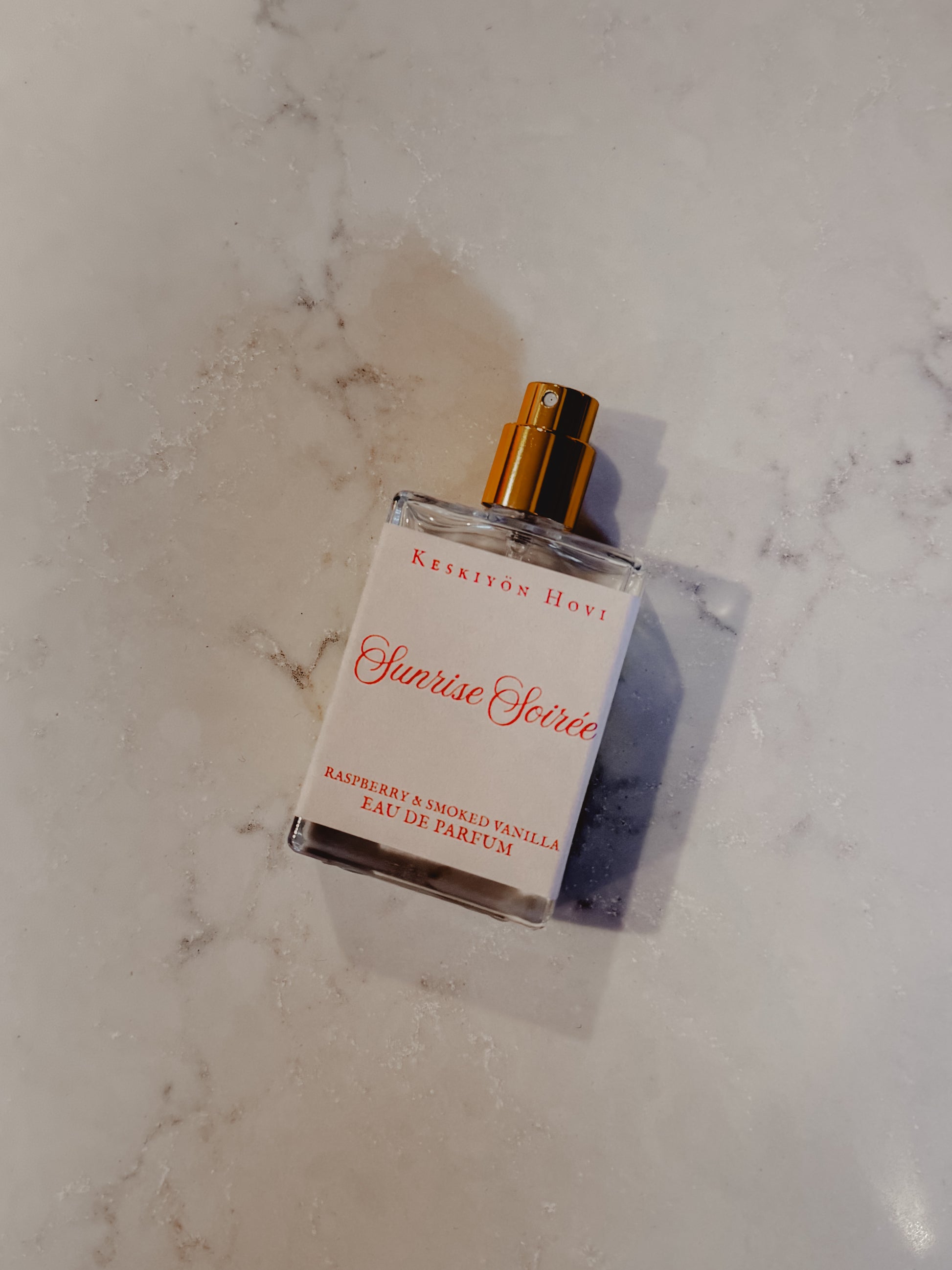 Perfume bottle labeled 'Sunrise Source' on a marble surface