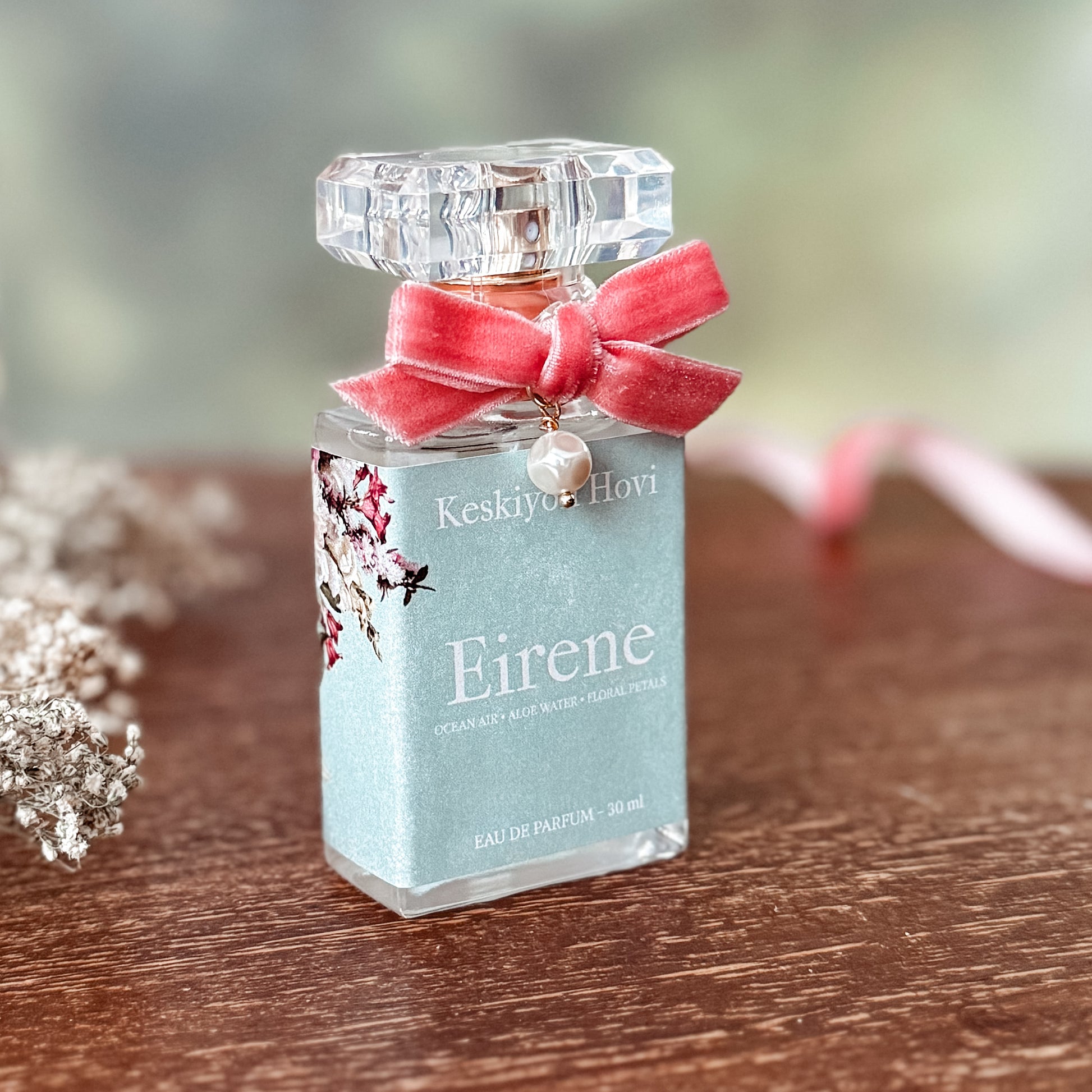 Perfume bottle labeled 'Eirene' with a pink bow on a wooden surface