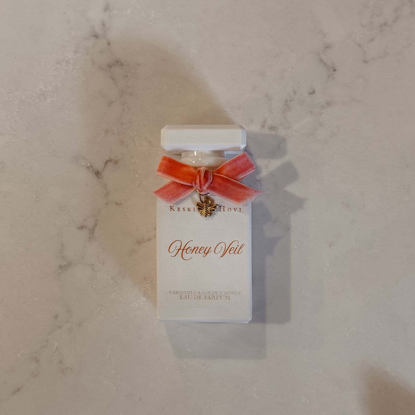 Perfume bottle with 'Honey Veil' packaging on a marble surface