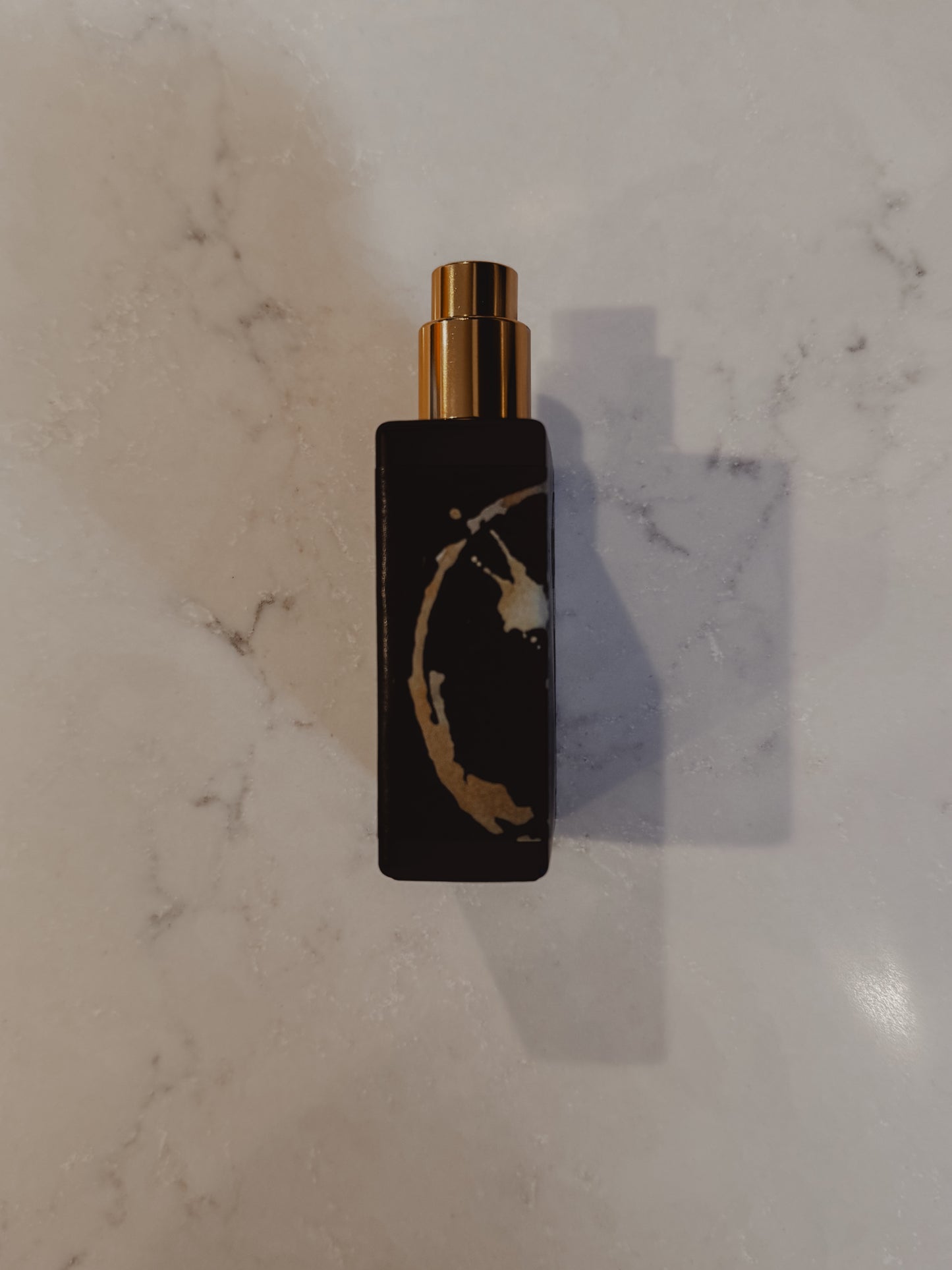 Black and gold perfume bottle on a marble surface