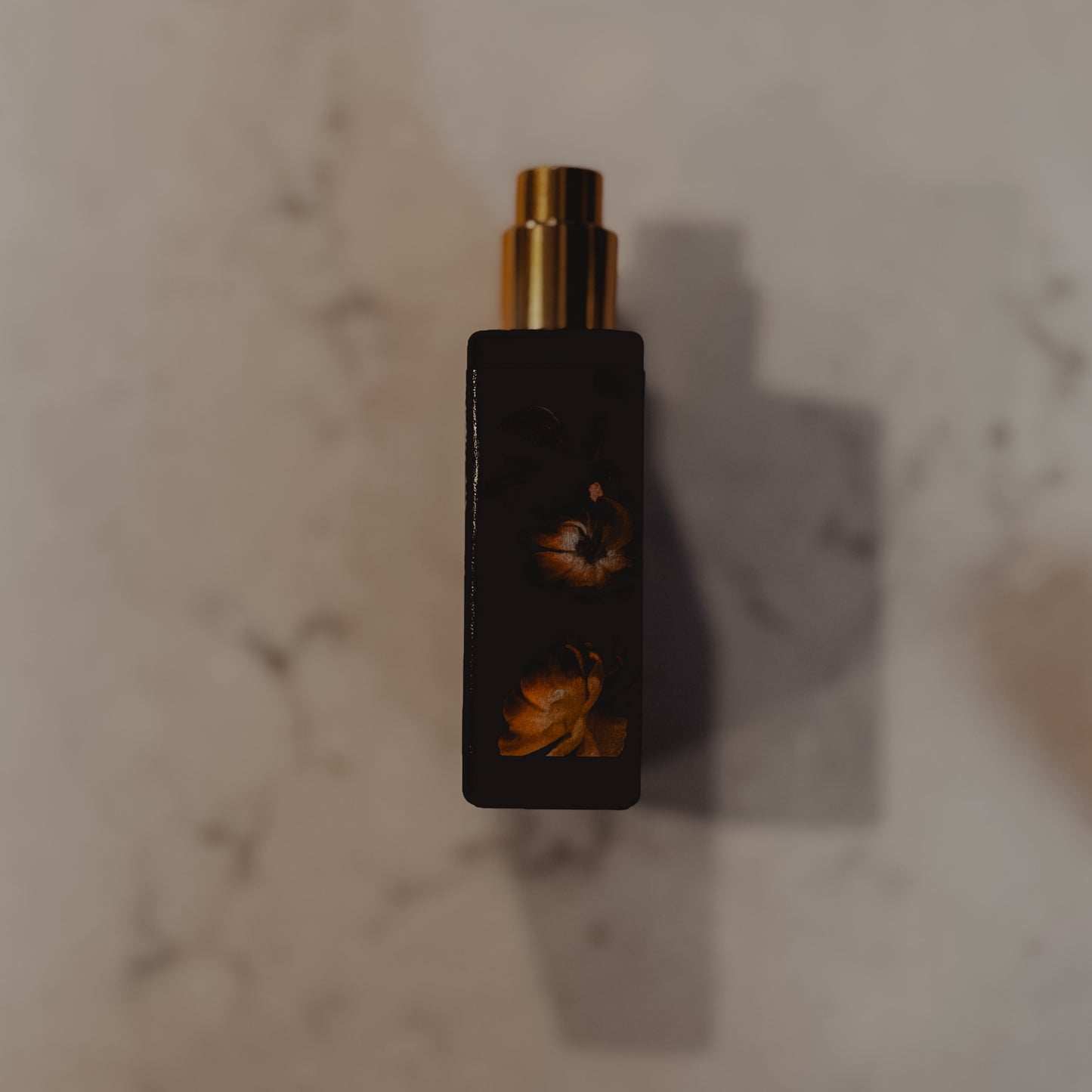Black perfume bottle with gold cap on a marble surface