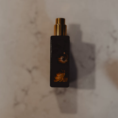 Black perfume bottle with gold cap on a marble surface