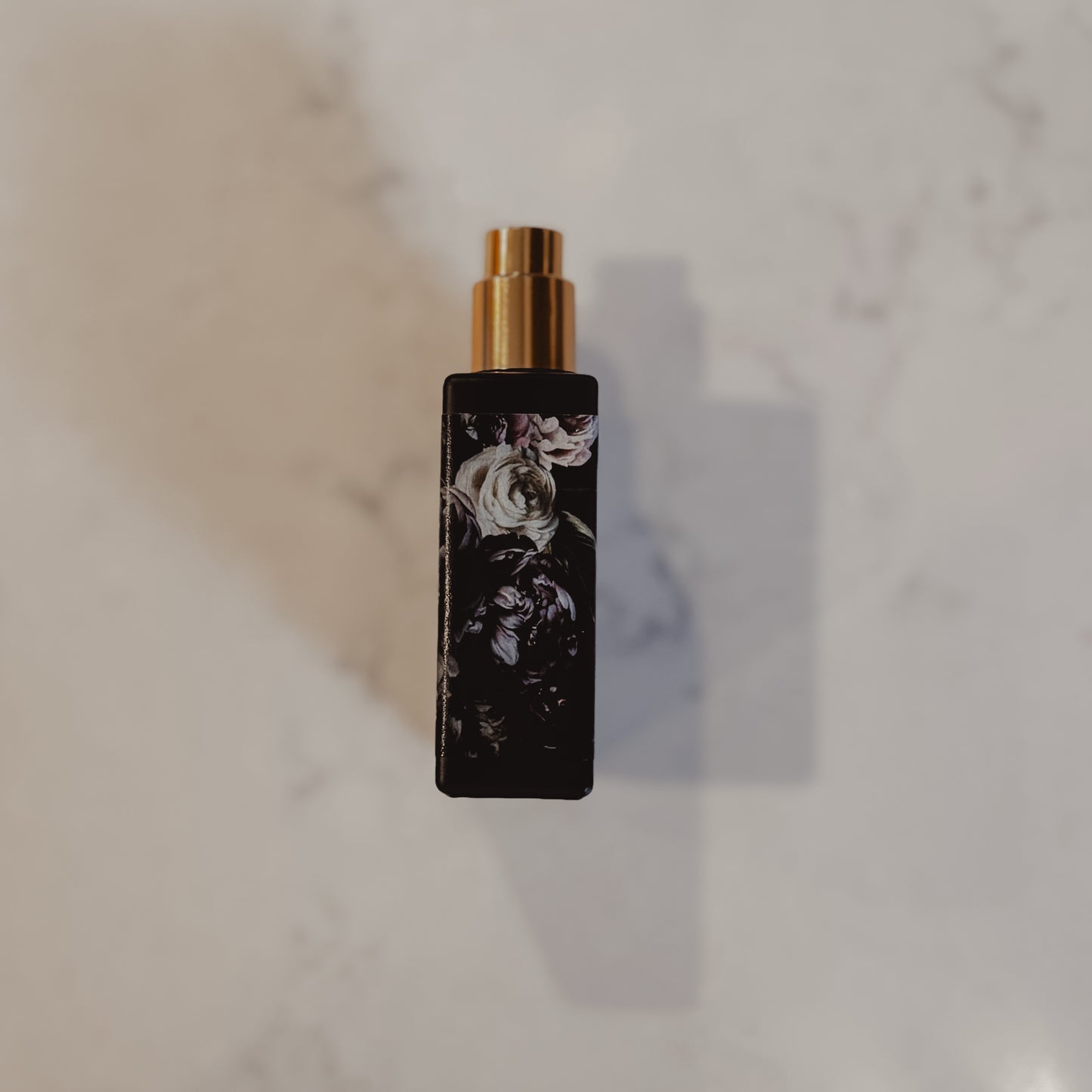 Black perfume bottle with gold cap on a marble surface