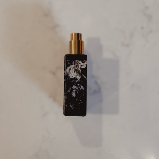 Black perfume bottle with gold cap on a marble surface