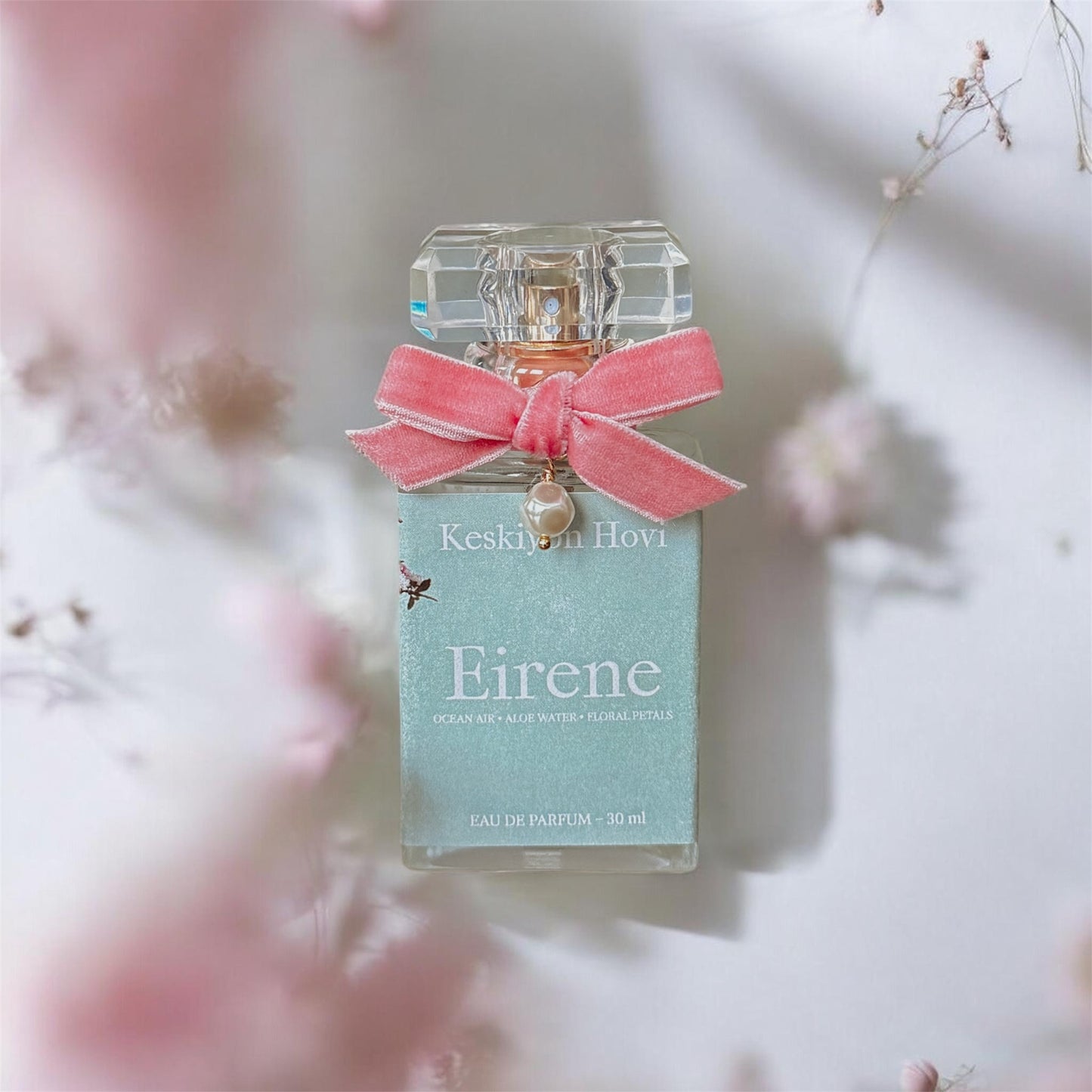 Perfume bottle with a pink bow labeled 'Eirene' on a soft floral background
