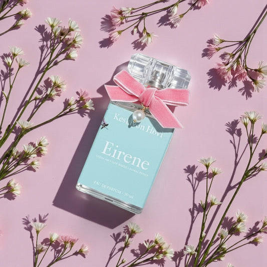 Perfume bottle with pink bow and 'Eirene' label on a pink floral background