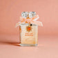 Perfume bottle with a bow and decorative elements on a pink background