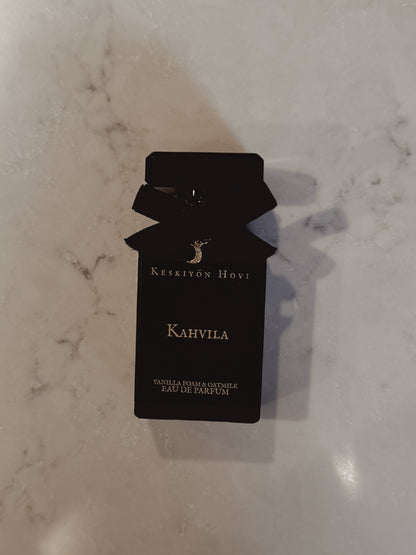 Black perfume bottle-shaped card with 'Keskivön Hovi' branding on a marble surface