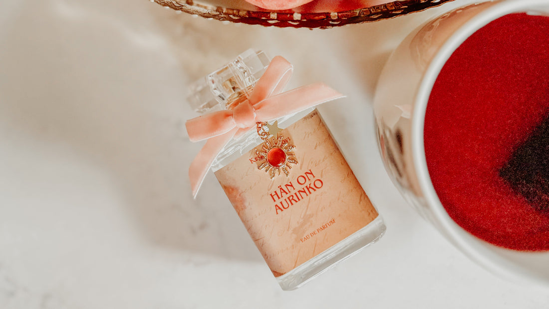 Small bottle of HAN ON AURINKO with a pink bow, peaches, and a cup on a light surface.