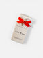 Perfume bottle with a red ribbon and decorative tag on a white background