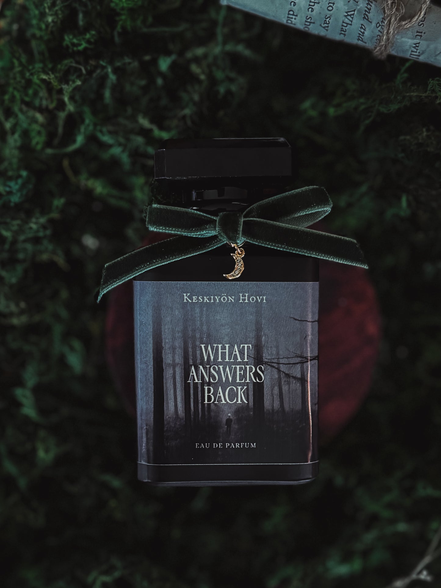 Perfume bottle with a green velvet ribbon on a textured green background