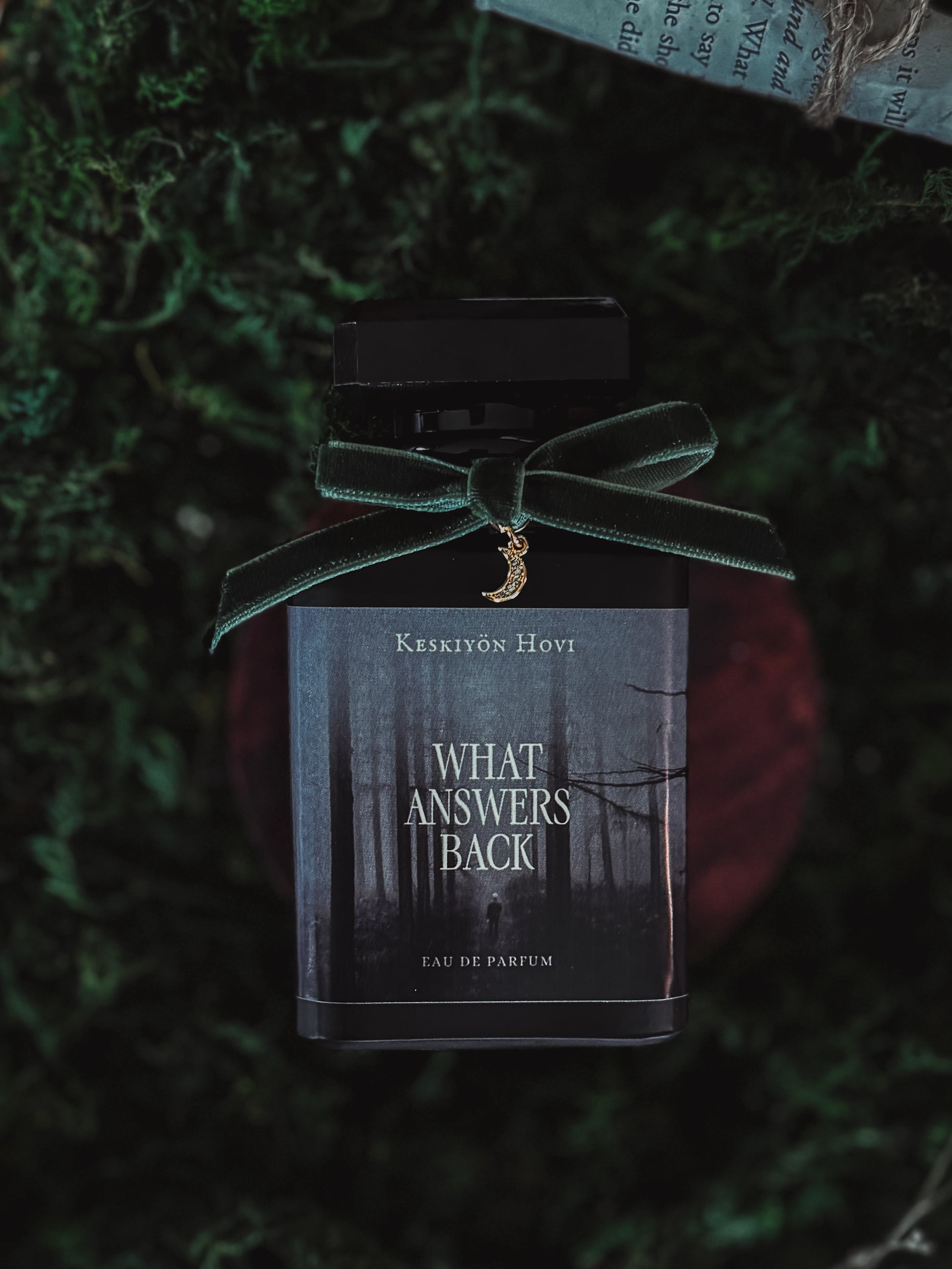 Perfume bottle with a green velvet ribbon on a textured green background