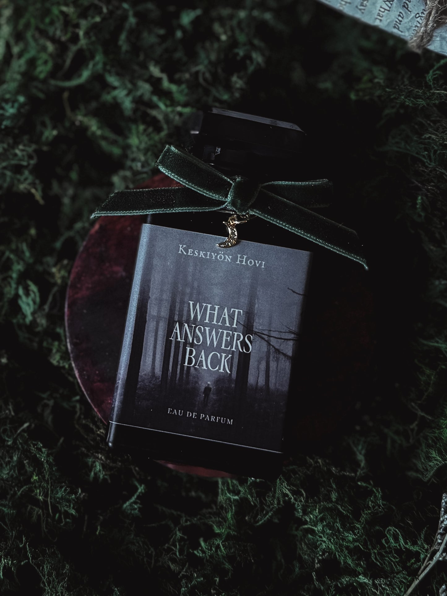 Perfume bottle with a dark label on a green textured surface