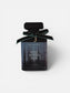 Perfume bottle with a black label and green ribbon on a white background