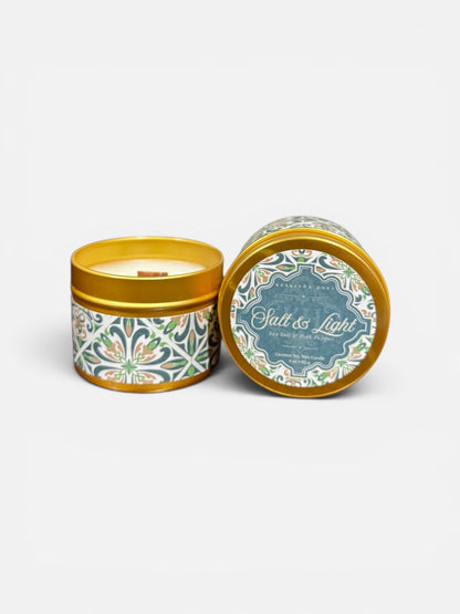 Candle in a decorative tin with 'Salt & Light' branding on a white background