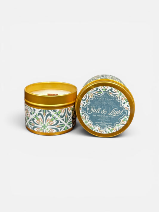Candle in a decorative tin with 'Salt & Light' branding on a white background