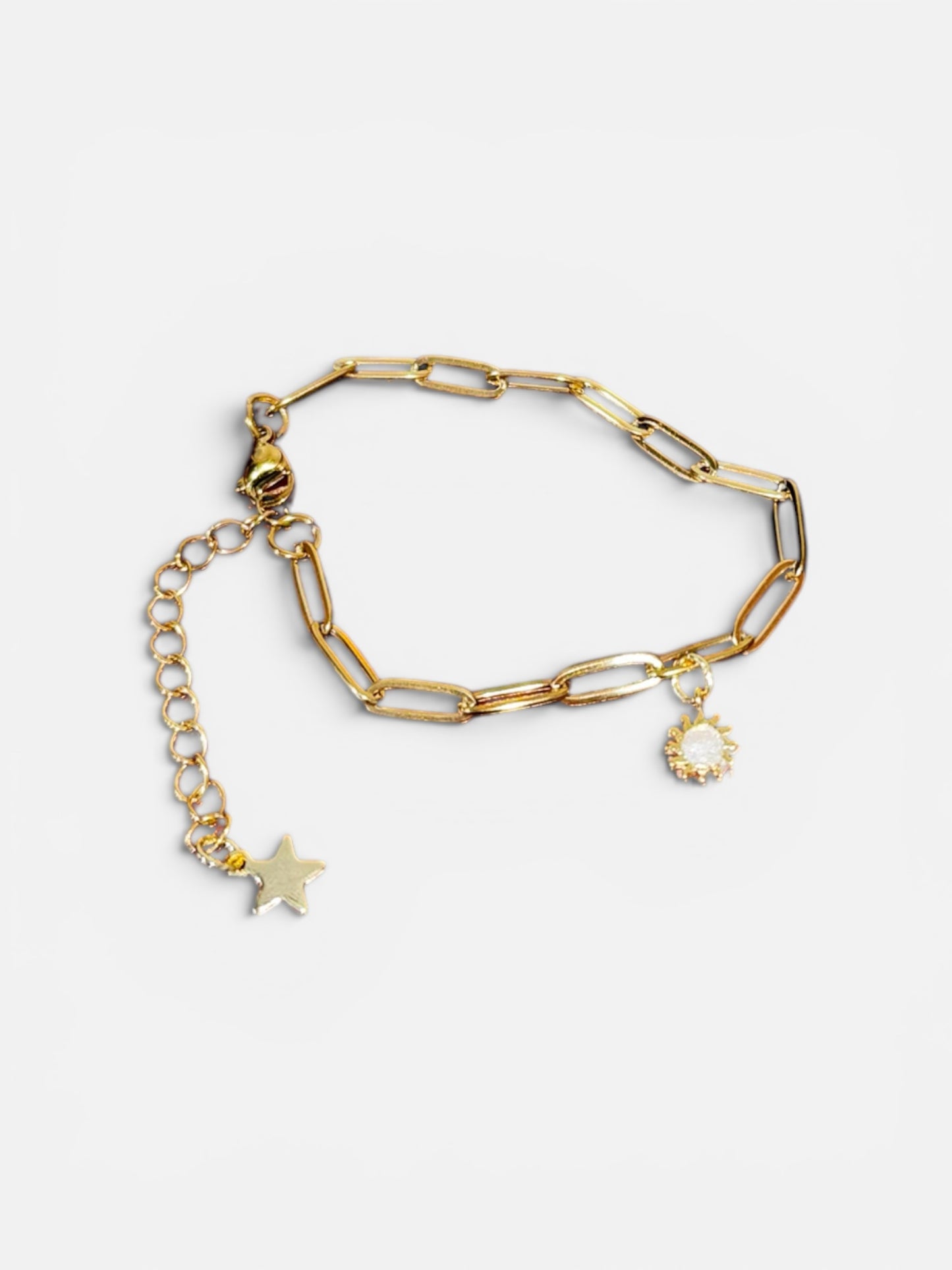 Gold chain bracelet with a sun and moon charms on a white background