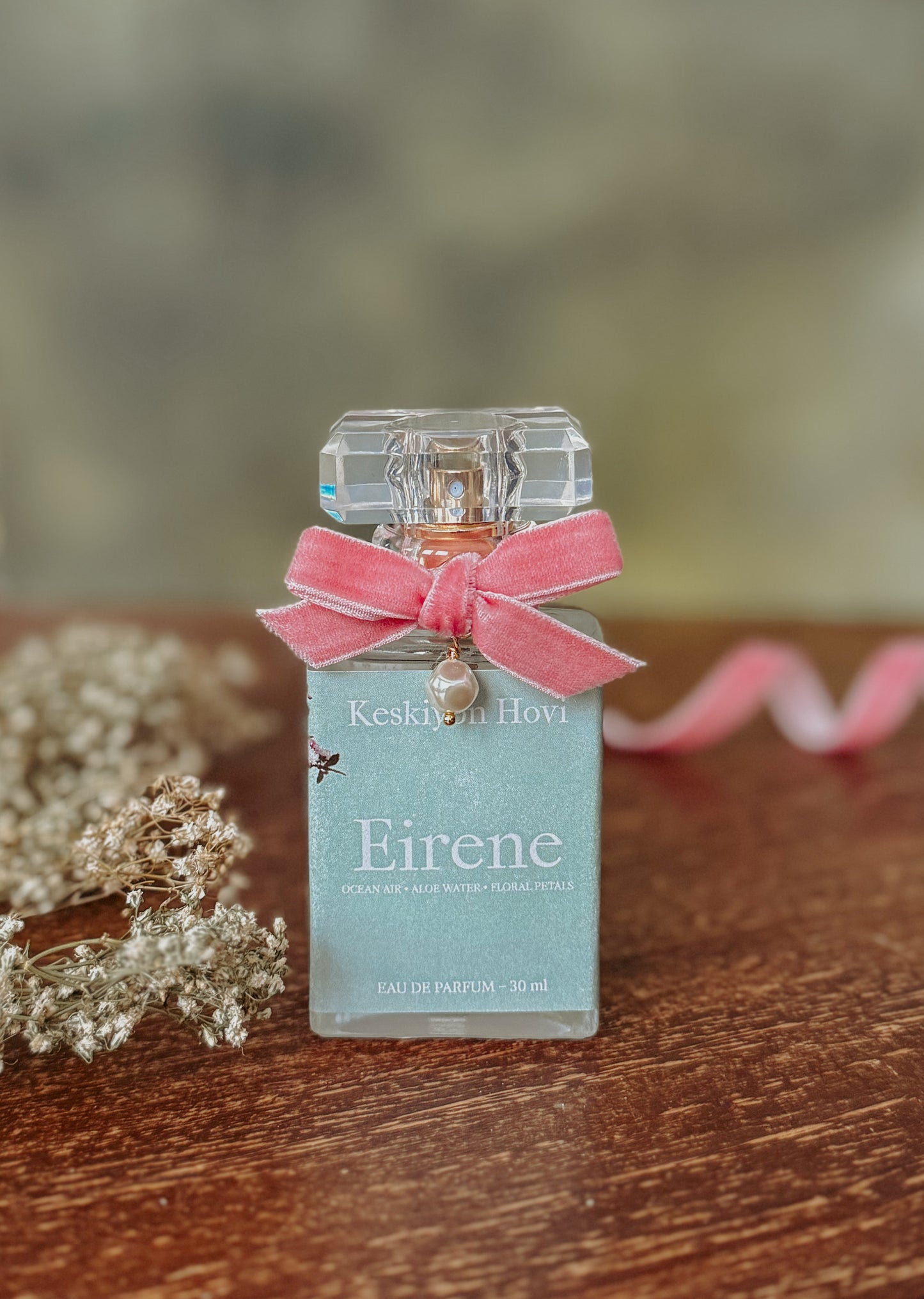 Perfume bottle labeled 'Eirene' with a pink bow on a wooden surface