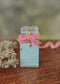 Perfume bottle labeled 'Eirene' with a pink bow on a wooden surface